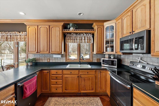 kitchen featuring dark countertops, appliances with stainless steel finishes, plenty of natural light, and a sink