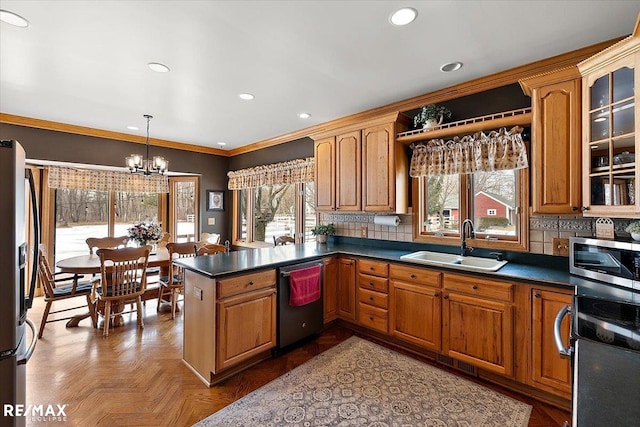 kitchen with a peninsula, decorative backsplash, stainless steel appliances, and a sink