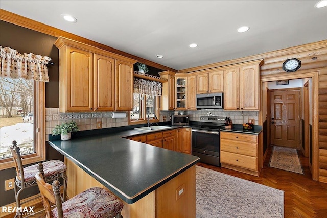 kitchen with dark countertops, appliances with stainless steel finishes, a peninsula, a sink, and recessed lighting