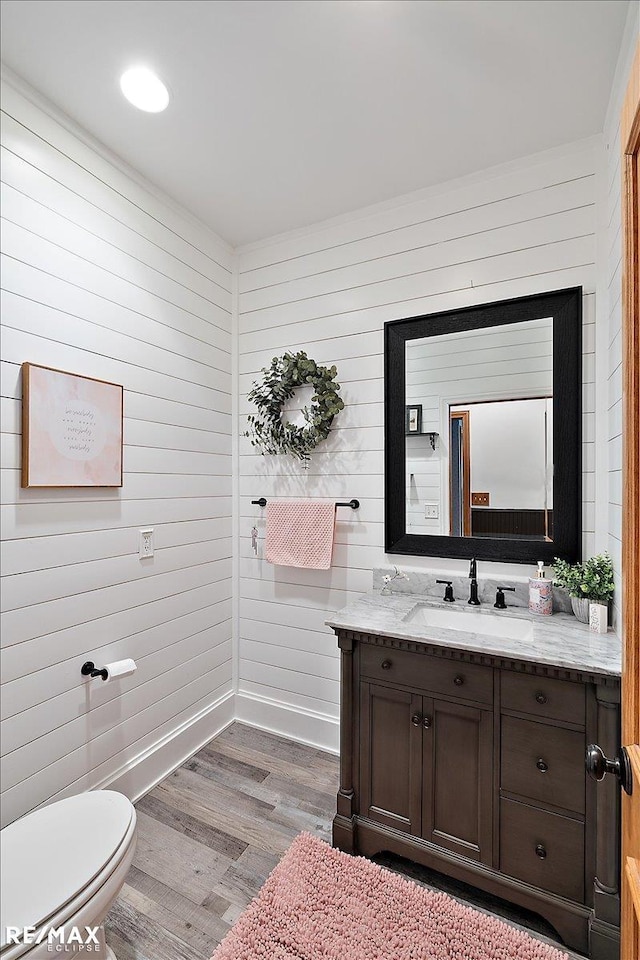 bathroom featuring toilet, vanity, baseboards, and wood finished floors