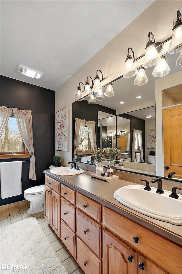 full bathroom with toilet, a wealth of natural light, tile patterned flooring, and a sink