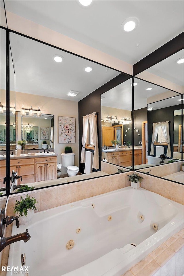 bathroom with a jetted tub, vanity, toilet, and recessed lighting