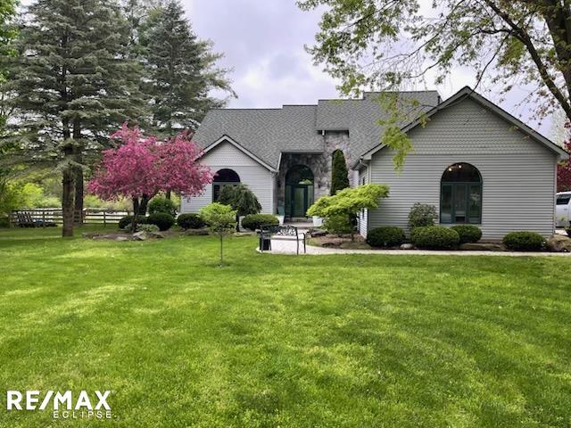 view of front of home featuring a front yard, stone siding, and fence