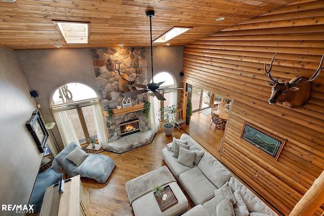 unfurnished living room featuring wood ceiling, high vaulted ceiling, wood finished floors, and a stone fireplace