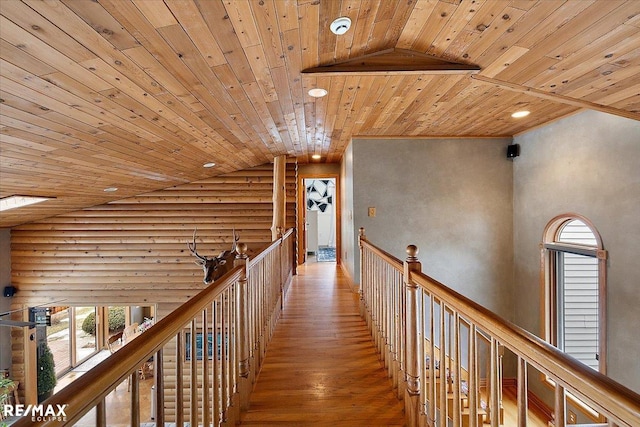 corridor featuring high vaulted ceiling, wood-type flooring, wood ceiling, an upstairs landing, and rustic walls