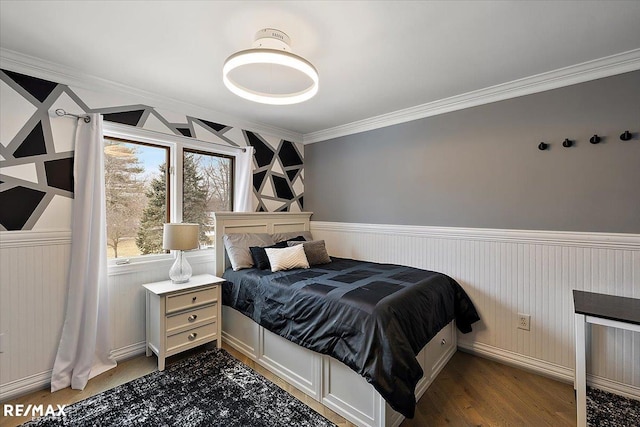 bedroom with wood finished floors, crown molding, and wainscoting