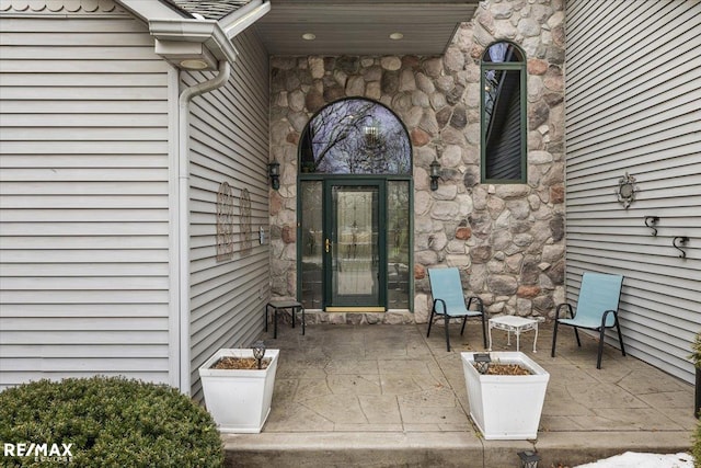 entrance to property with stone siding and a patio