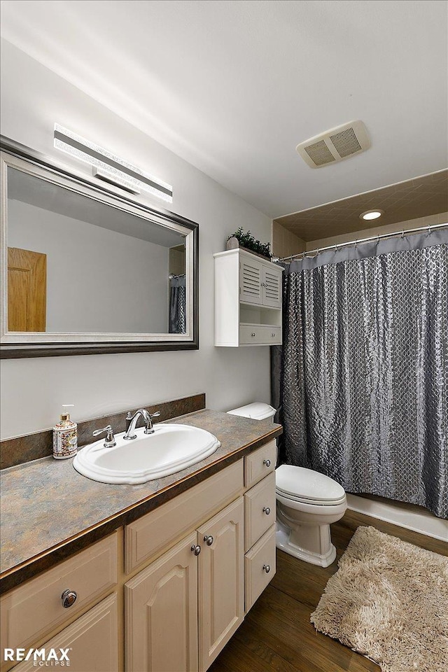 full bath with visible vents, a shower with shower curtain, toilet, vanity, and wood finished floors