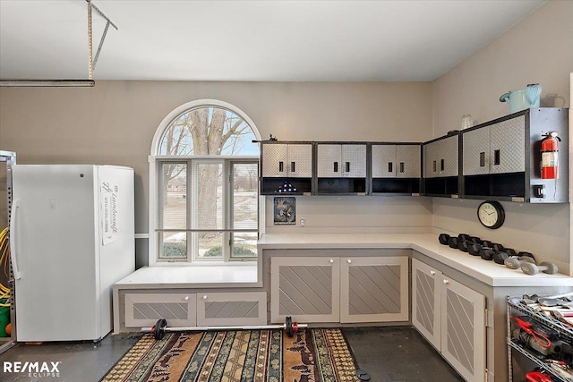 kitchen with light countertops, concrete flooring, and freestanding refrigerator