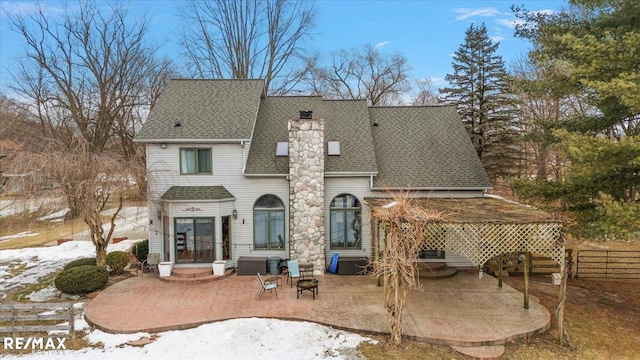 rear view of house with roof with shingles, a chimney, fence, and a patio