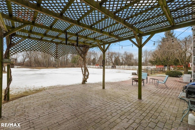 snow covered patio featuring fence and a pergola