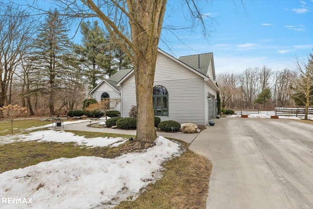 view of property exterior with a garage, fence, and concrete driveway