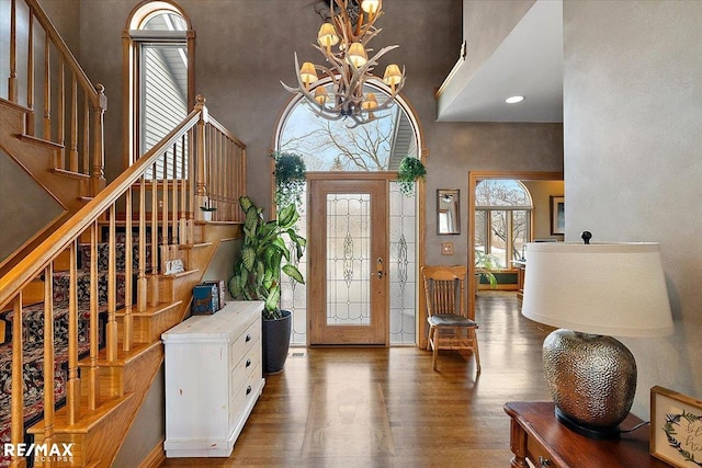 entryway featuring a notable chandelier, a high ceiling, stairway, and wood finished floors