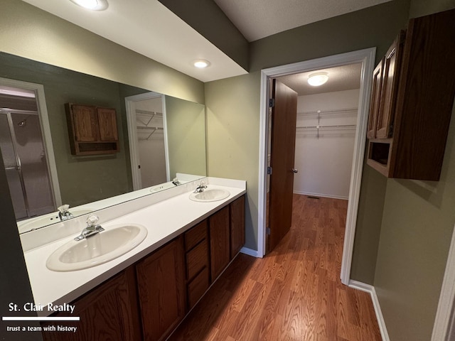 full bath featuring double vanity, a sink, and wood finished floors