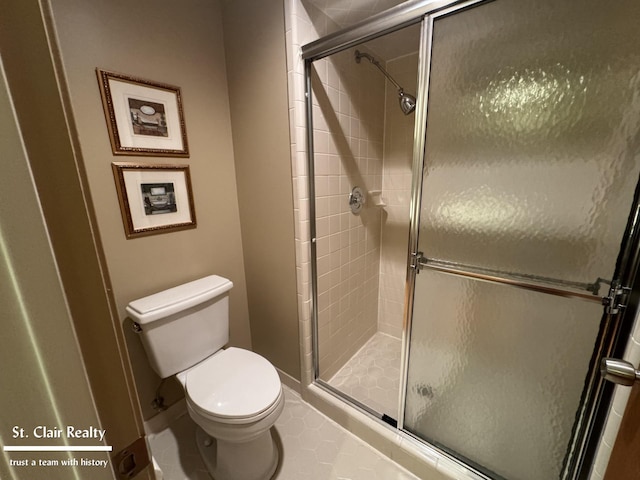 full bathroom with toilet, a shower stall, and baseboards