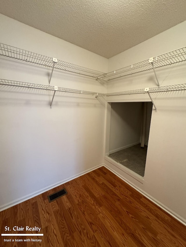 spacious closet featuring visible vents and wood finished floors