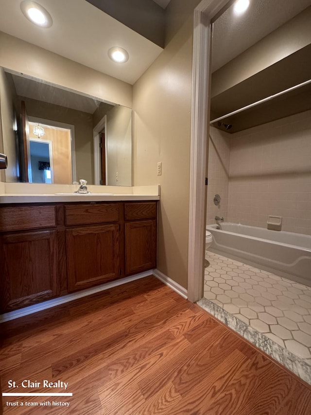 full bathroom featuring toilet, tub / shower combination, vanity, wood finished floors, and baseboards