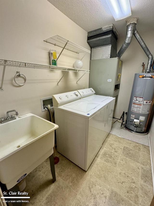 clothes washing area featuring laundry area, independent washer and dryer, a textured ceiling, water heater, and a sink