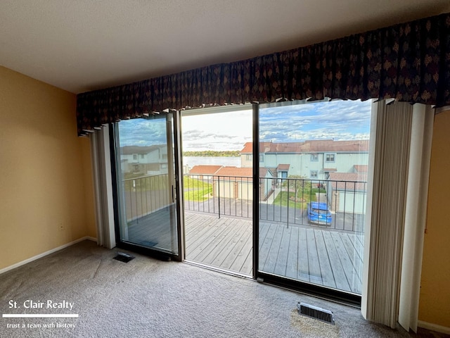 doorway to outside featuring carpet floors, baseboards, a residential view, and visible vents