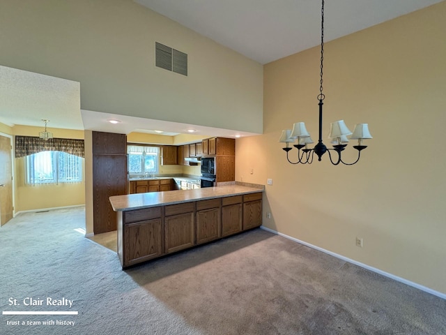 kitchen featuring a peninsula, brown cabinetry, visible vents, and light colored carpet