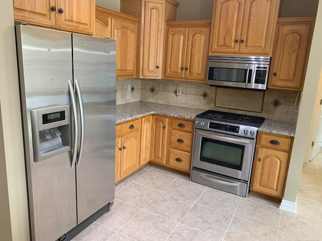 kitchen with light stone countertops, light tile patterned floors, and appliances with stainless steel finishes