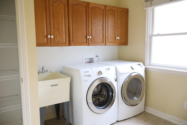 laundry room with light tile patterned flooring, washing machine and dryer, cabinet space, and a healthy amount of sunlight