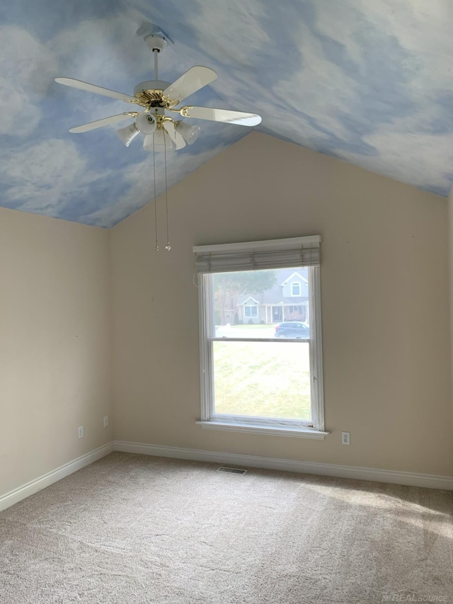 carpeted spare room with vaulted ceiling, a ceiling fan, visible vents, and baseboards