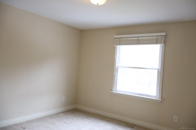 empty room featuring carpet, visible vents, and baseboards