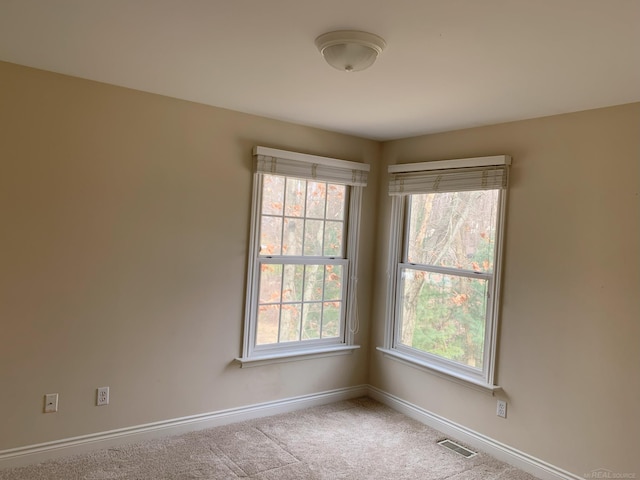 carpeted spare room featuring visible vents and baseboards