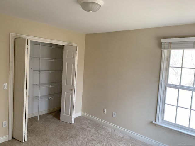 unfurnished bedroom with light carpet, baseboards, and a closet