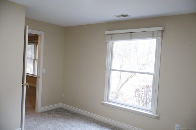 carpeted spare room featuring visible vents and baseboards