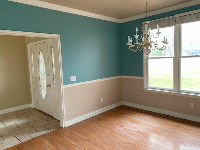 entryway featuring wood-type flooring, visible vents, an inviting chandelier, ornamental molding, and baseboards