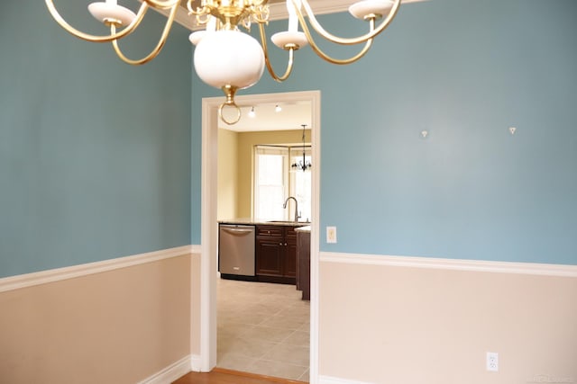 corridor featuring baseboards, light tile patterned floors, a sink, and an inviting chandelier