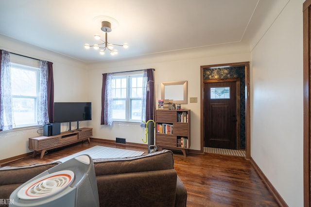 living area with a chandelier, visible vents, baseboards, and wood finished floors