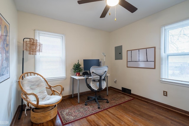 office area featuring a ceiling fan, electric panel, baseboards, and wood finished floors