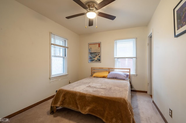 bedroom with light colored carpet, multiple windows, and baseboards