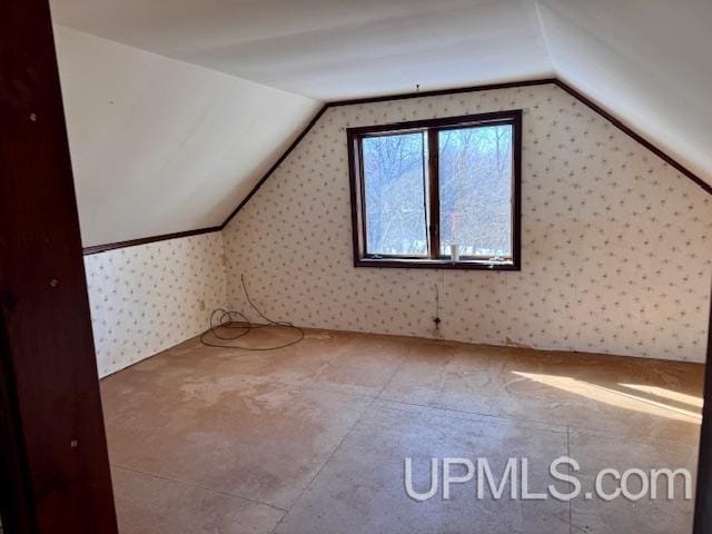 bonus room with vaulted ceiling and wallpapered walls