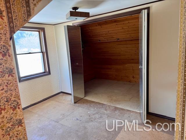 interior space featuring baseboards and wallpapered walls