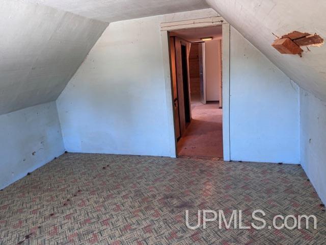 bonus room featuring lofted ceiling and carpet flooring