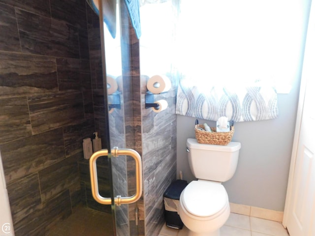 bathroom featuring tile patterned flooring, a shower stall, toilet, and baseboards