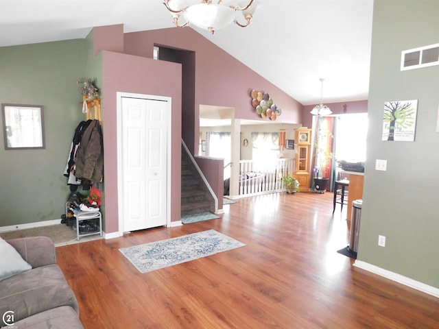 living area with stairway, wood finished floors, visible vents, and baseboards