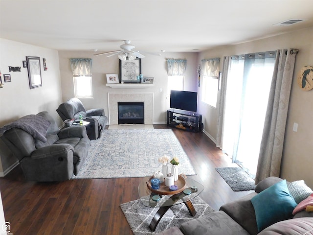 living area with a fireplace, visible vents, ceiling fan, wood finished floors, and baseboards