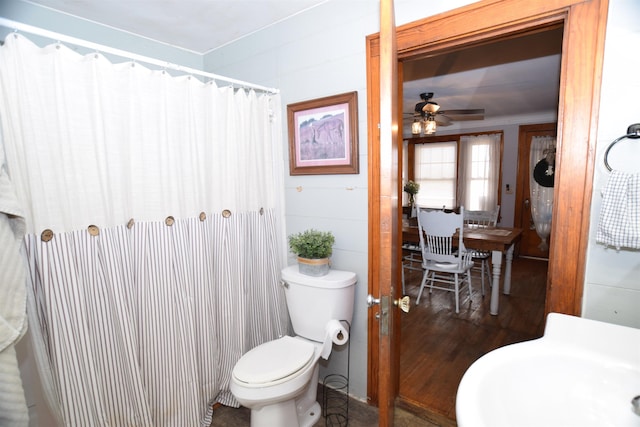 bathroom with a shower with shower curtain, a sink, toilet, and ceiling fan