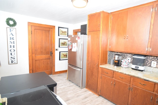 kitchen featuring light wood-style floors, freestanding refrigerator, light countertops, and decorative backsplash