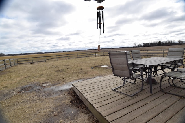 wooden deck featuring a rural view, fence, and outdoor dining space