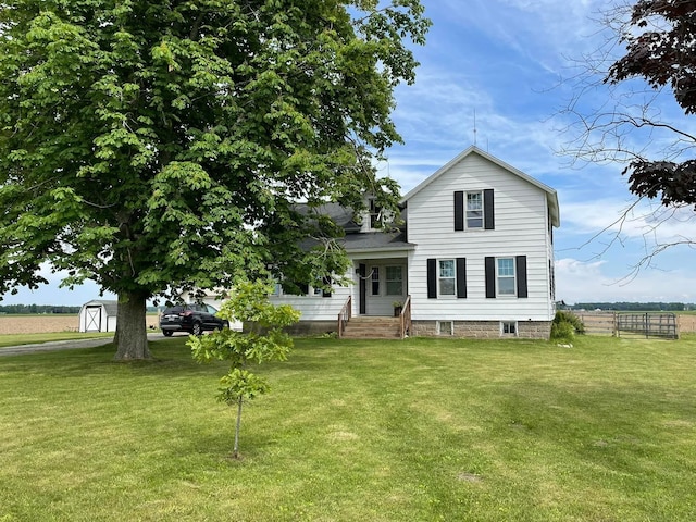 view of front of house with a storage unit, fence, a front lawn, and an outdoor structure