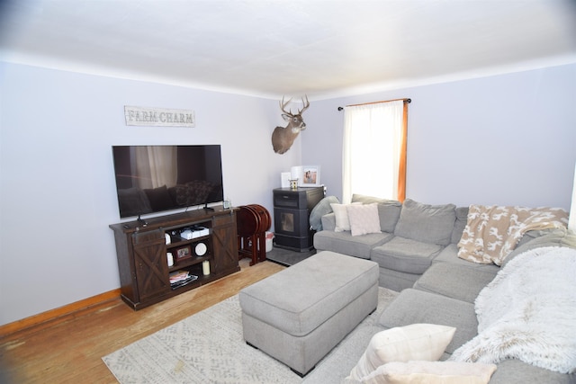 living area with a wood stove, light wood-style flooring, and baseboards