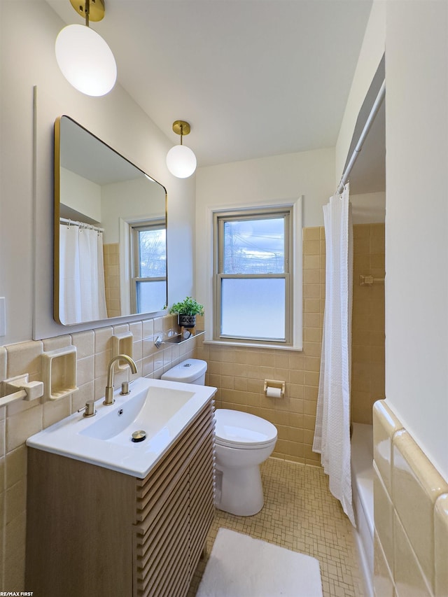 bathroom featuring toilet, a wainscoted wall, tile walls, and vanity