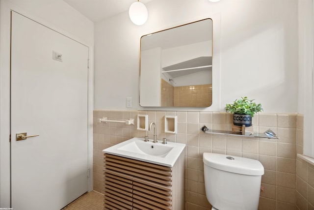 bathroom with a wainscoted wall, tile walls, toilet, and vanity