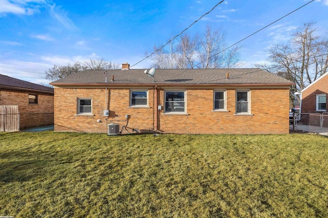 back of house with a yard, brick siding, and fence